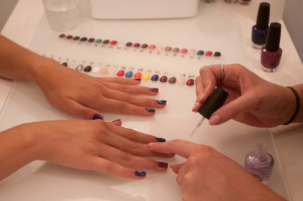 <p>Journalism junior Hannah Watts, left, gets her nails painted by Okemos, Mich., resident Morgane Dalton on Sept. 10, 2014, at Heat Blow Dry and Beauty Boutique, 2900 Hannah Blvd. Jessalyn Tamez/The State News</p>