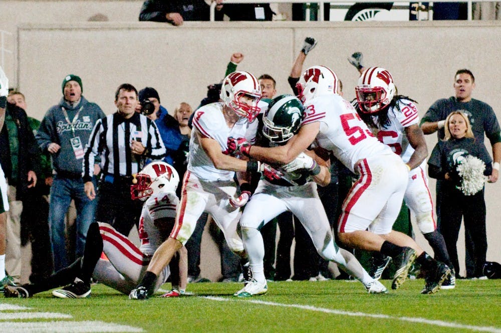 Senior wide receiver Keith Nichol fights with Wisconsin defenders to get the ball in the endzone. After an official review, the play was called a touchdown and as a result MSU won the game. The Spartans defeated Wisconsin, 37-31, on Saturday night at Spartan Stadium. Josh Radtke/The State News