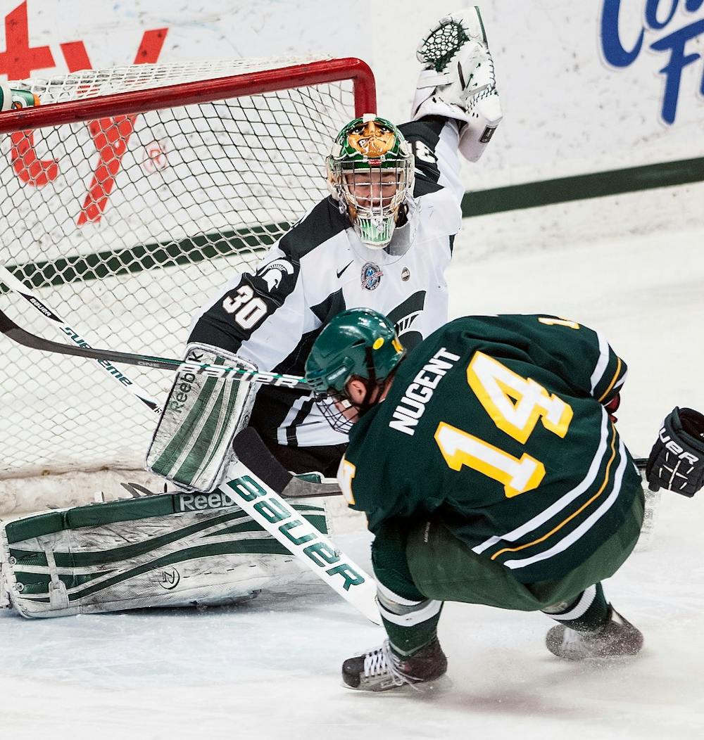 	<p>Freshman goaltender Jake Hildebrand makes a save on Northern Michigan forward Brian Nugent on Friday, Feb. 15, 2013, at Munn Ice Arena. The Wildcats defeated the Spartans, 5-3, during the first game of the weekend series. Adam Toolin/The State News</p>