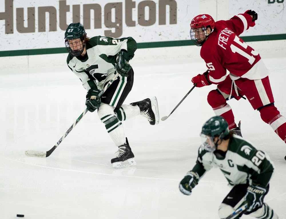 Freshman forward Mason Appleton, 27, and Wisconsin forward Matthew Freytag, 15, skate to take possession of the puck during the hockey game against Wisconsin on Dec. 11, 2015 at Munn Ice Arena. The Spartans defeated the Badgers, 4-3.