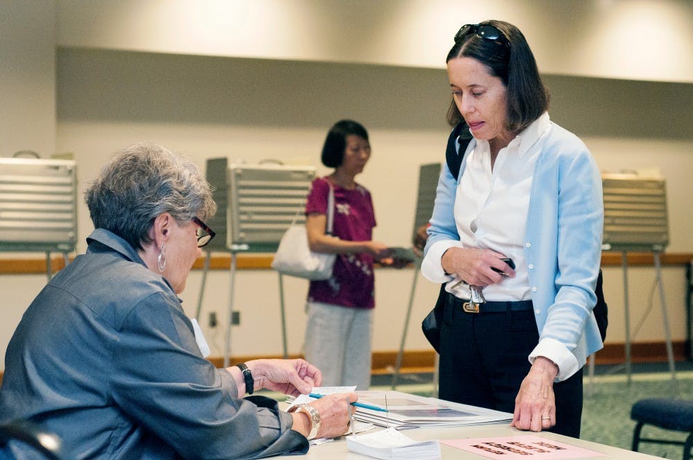 Volunteer Sharon Krinock helps East Lansing resident Kathy Bouchard-Wyant finish voting at the Hannah Community Center, 819 Abbot Road, on Aug. 7, 2012. "I think it's everyone's duty to come out and vote," Bouchard-Wyant said. "Everyone has a voice." Julia Nagy/The State News
