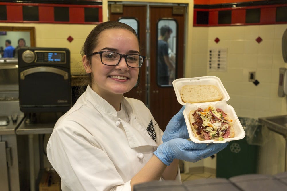 <p>&nbsp;Elementary education sophomore Alison Deboodt is pictured with QUE’s smoked brisket sandwich at the International Center on Jan. 7, 2019. The other proteins available are pulled pork and smoked Michigan turkey.&nbsp;</p>