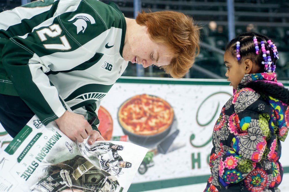<p>Freshman forward Mason Appleton signs an autograph for Lansing resident Caitlyn Warren, 4, during a meet and greet with the MSU Men's Hockey team on Nov. 16, 2015 in Munn Ice Arena. When Appleton asked Warren what her name was, she replied, "It starts with a C, and rhymes with Caitlyn." Warren's mother, Tamara Warren said that her daughter pleaded with her all day to attend the meet and greet event. </p>