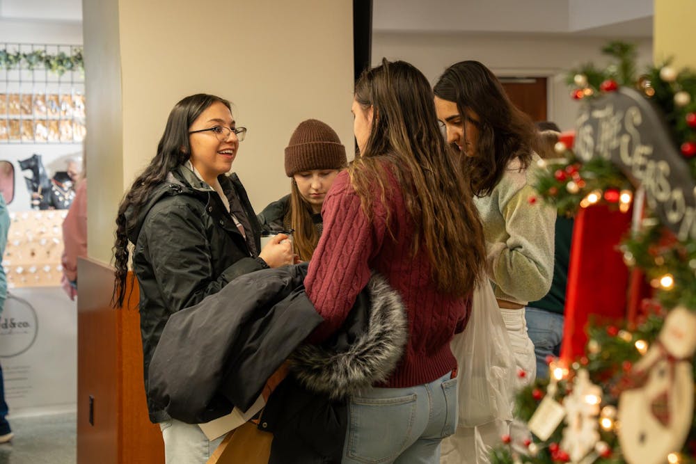Lauren Chesla laughs with friends Emma Steury, Miranda Kelly and Madelyn Buck at Michigan State’s annual winter arts and craft show at the Union on campus in East Lansing, Mich., on Saturday, Dec. 6, 2025.