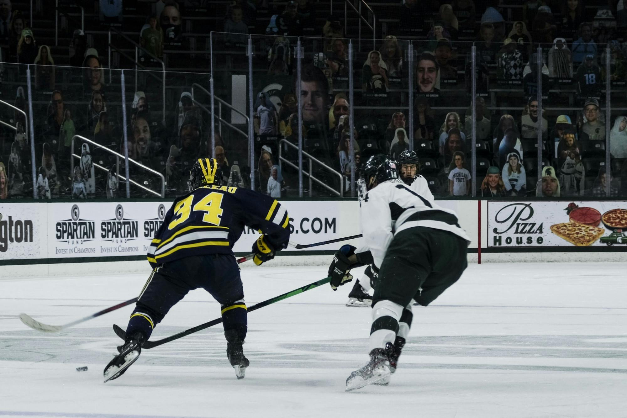 <p>Junior forward Adam Goodsir (14) attempts to steal the puck from Michigan on Jan. 9, 2021, at the Munn Ice Arena. The Spartans defeated the Wolverines, 3-2.</p>