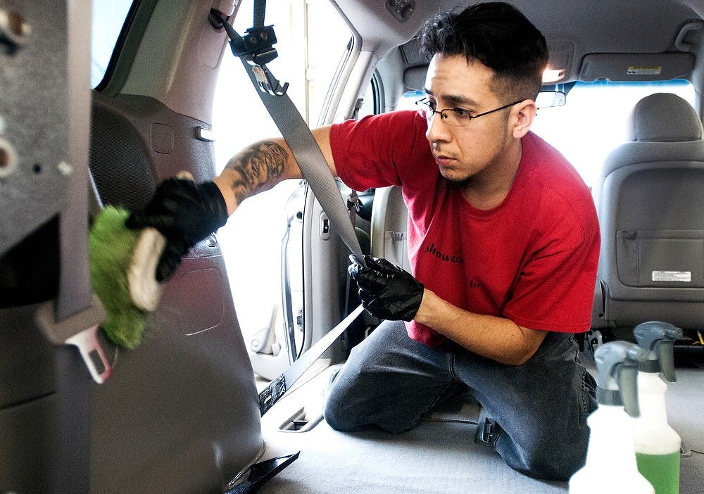 	<p>Lansing resident Luis Serna scrubs the inside of a car, April 23, 2013, at Showroom Shine, 248 Grand River Avenue. A line of cars were in the shop waiting for Serna and another employee to heavily clean the interior front to back. Adam Toolin/The State News</p>