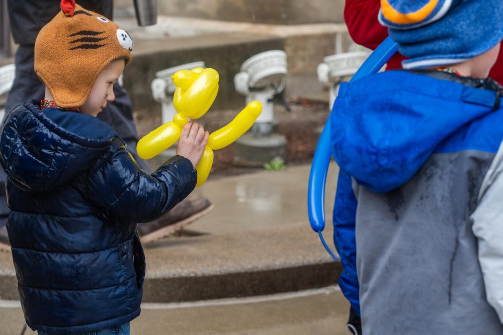 <p>Hudson Spilling looks at his new balloon dog at an Easter egg hunt on the Capitol lawn in Lansing, MI, on Saturday, March 30, 2024. Families stood under umbrellas and kids ran up and down the Capitol steps during the holiday event.</p>