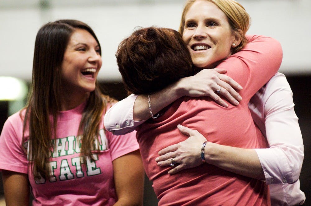 Gymnastics head coach Kathie Klages hugs Angela Montie, right, who is a 1995 alumna of the gymnastics team, as Megan Bergland, left, stands by on Saturday at Jenison Field House after the meet against Minnesota. Bergland is also an alumna who graduated in 2010. The meet commemorated past members of the gymnastics team. Lauren Wood/The State News