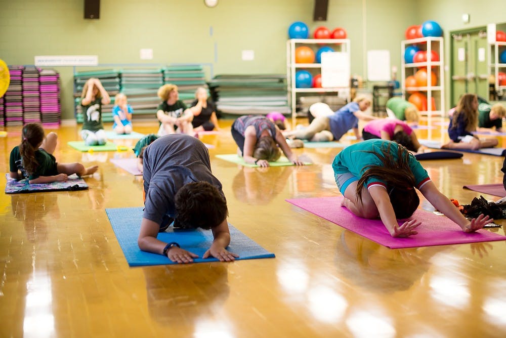<p>From left Ann Arbor, Mich., residents Zak and Sierra Kratz practice yoga June 24, 2014, at IM Sports-East. Grandparents University allows many grandparents the opportunity to bond with their grandchildren. Hayden Fennoy/The State News</p>