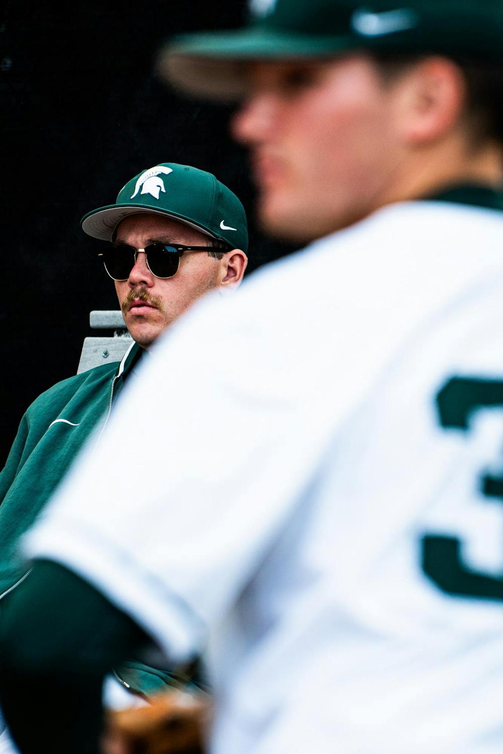 An MSU baseball player watches graduate pitcher Zach Maxey (32) throw a bullpen session during a game at McLane Stadium on April 13, 2025.