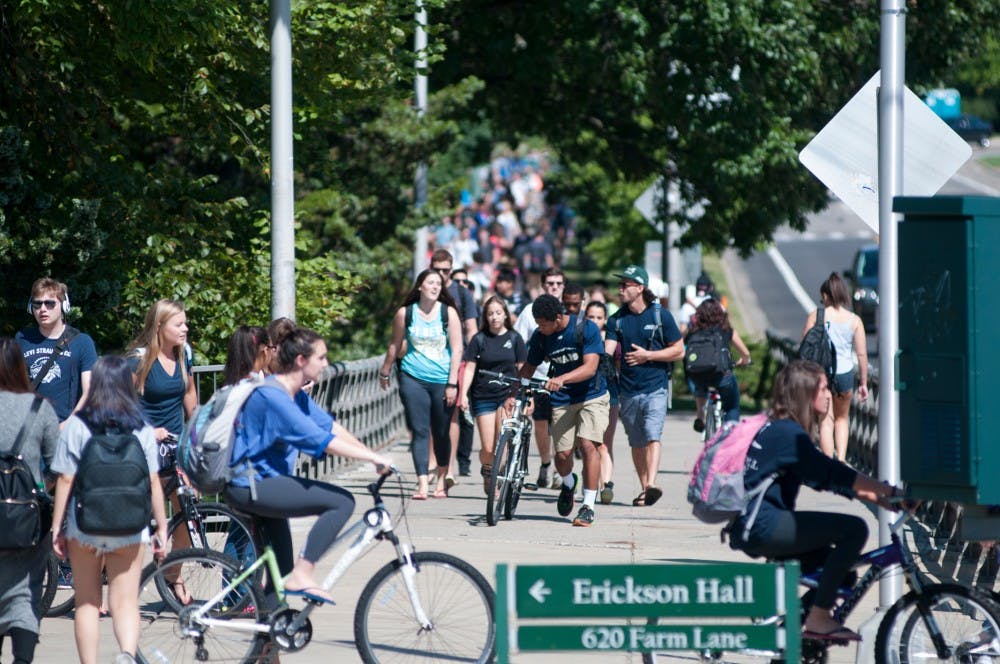 Cyclists and pedestrians head to class Sept. 10, 2015 on the bridge on Farm Lane. Bike traffic is a common issue for students on campus. Jack Stephan/ The State News