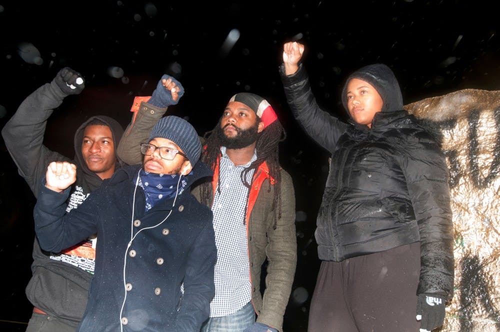 <p>Members of the Black Student Alliance stand in front of the rock on Nov. 12, 2015 at the Rock on Farm Lane. The group gathered to paint the rock and stand in solidarity with the black students at the University of Missouri. </p>