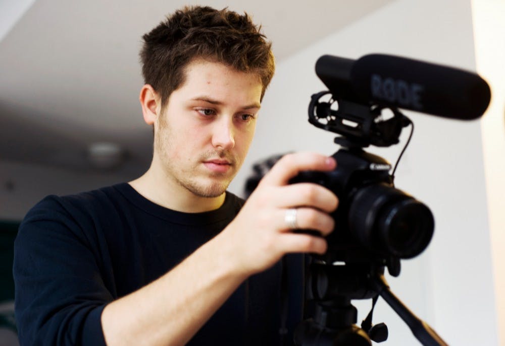 Media arts and technology senior Justin Grosjean checks the settings on his camera before filming a segment of a film project at his classmate's apartment on Tuesday afternoon. Grosjean is one of several MSU students that will be featured at the East Lansing Film Featival Nov. 9-17. Lauren Wood/The State News