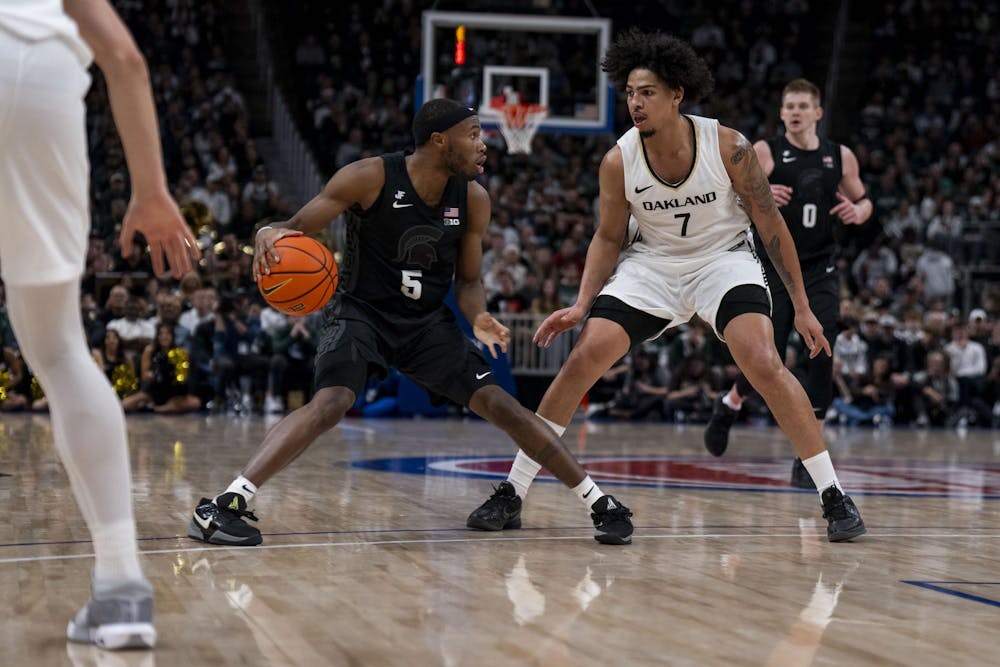 <p>Michigan State junior guard Tre Holloman (5) keeps the ball away from Oakland junior guard/forward Isaiah Jones (7) at Little Caesars Arena in Detroit on Dec. 17, 2024. The Spartans defeated the Golden Grizzlies 77-58.</p>