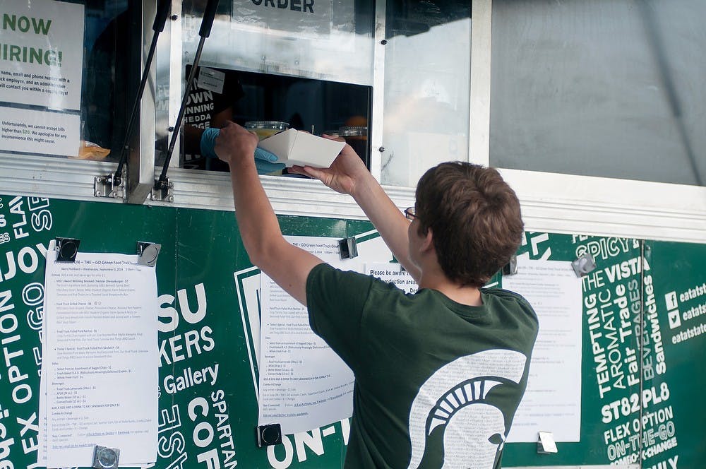 <p>Finance junior Jorgen Powell orders food from MSU's food truck on Sept. 3, 2014, outside Akers Hall. Students are able to use their meal plan passes to order food from the truck. Aerika Williams/The State News </p>