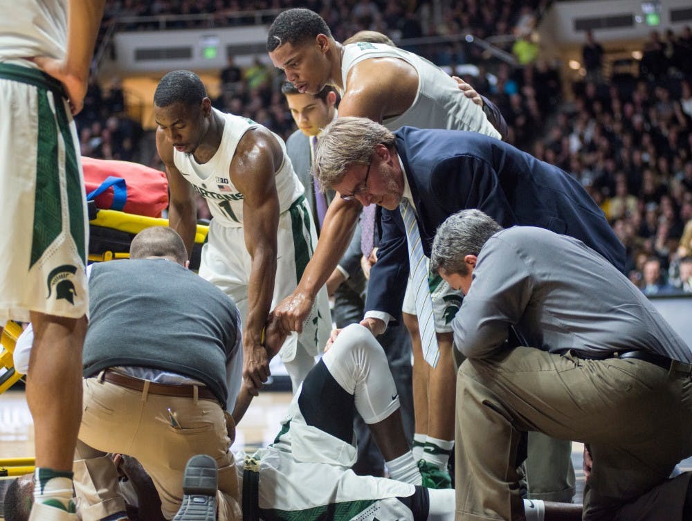 From left, junior guard Lourawls 'Tum Tum' Nairn Jr. (11) and freshman forward Miles Bridges hold the hand of red-shirt senior Eron Harris (14) after he takes a bad fall during the second half of the men's basketball game against Purdue on Feb. 18, 2017 at Mackey Arena in Lafayette, Ind. The Spartans were defeated by the boilermakers, 80-63.