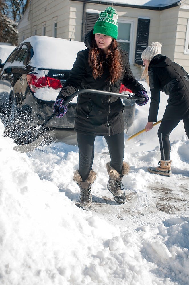 <p>Nursing senior Natalie Hoff shovels her driveway Monday afternoon after the snow storm Sunday. The storm left students living in houses to clear their sidewalks to abide by local ordinances. Kelsey Feldpausch/ The State News.</p>