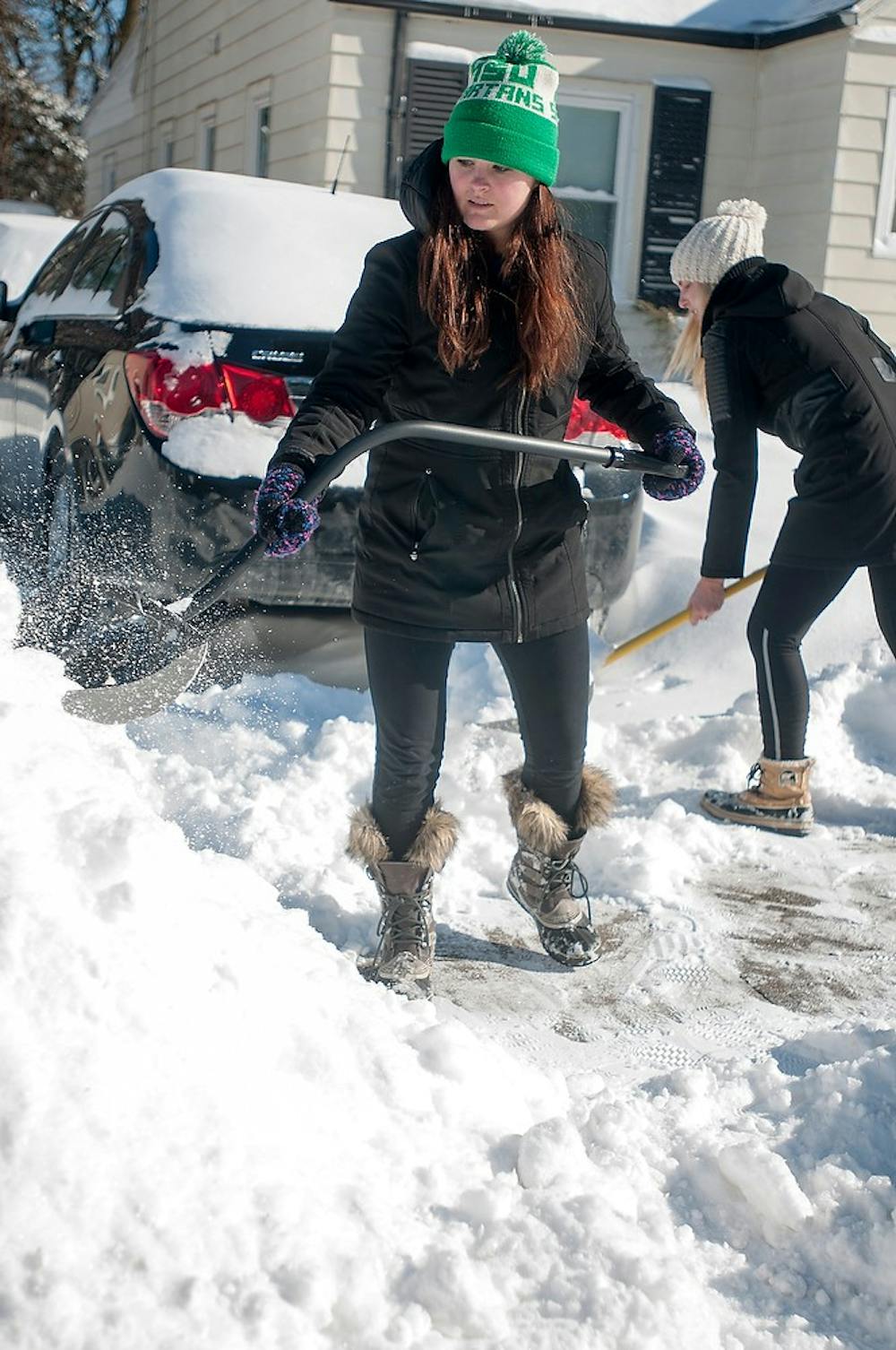 <p>Nursing senior Natalie Hoff shovels her driveway Monday afternoon after the snow storm Sunday. The storm left students living in houses to clear their sidewalks to abide by local ordinances. Kelsey Feldpausch/ The State News.</p>