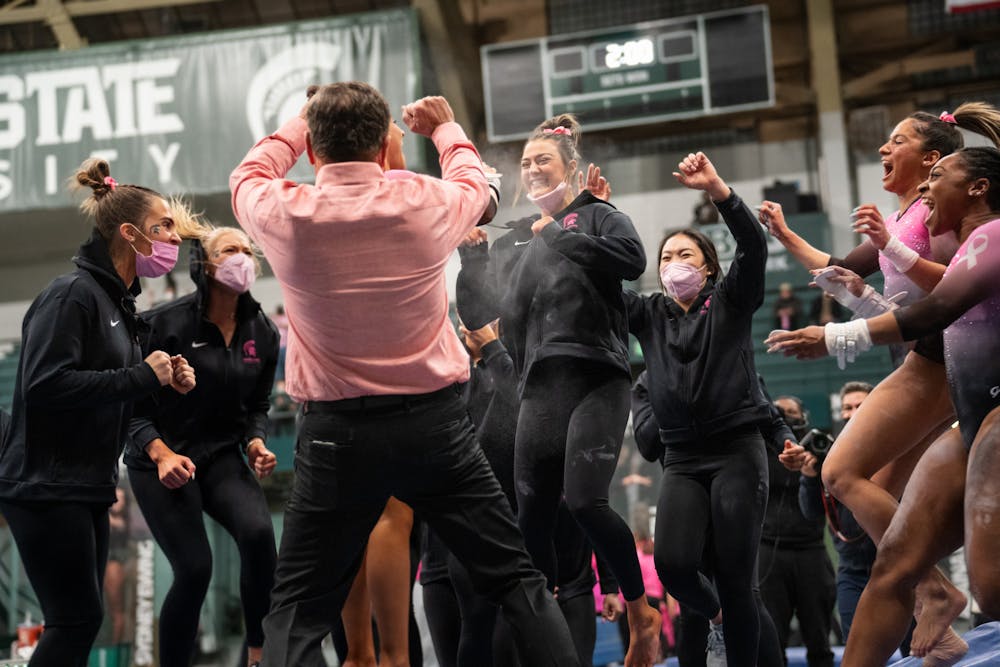 <p>The team cheers with sophomore Delanie Harkness after her bars routine in the Spartans&#x27; match against the University of Iowa Hawkeyes at Jenison Field House on Saturday, Jan. 22, 2022. </p>
