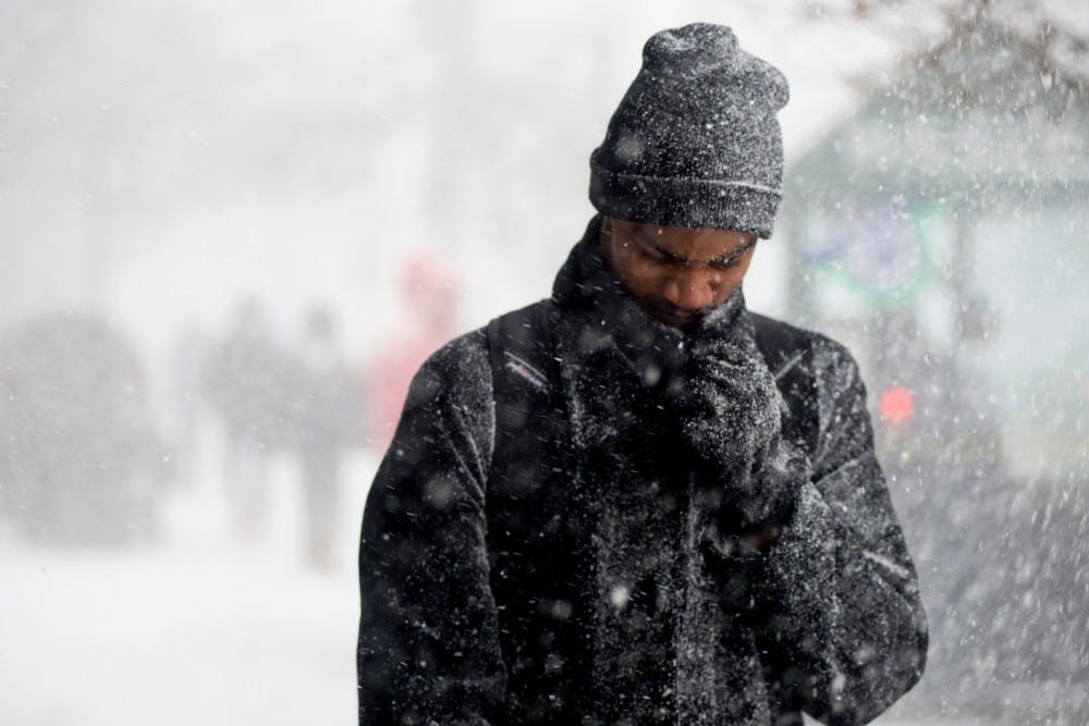 A man walks down Grand River on Dec. 18, 2015 during a brief snow storm in East Lansing, Mich. 