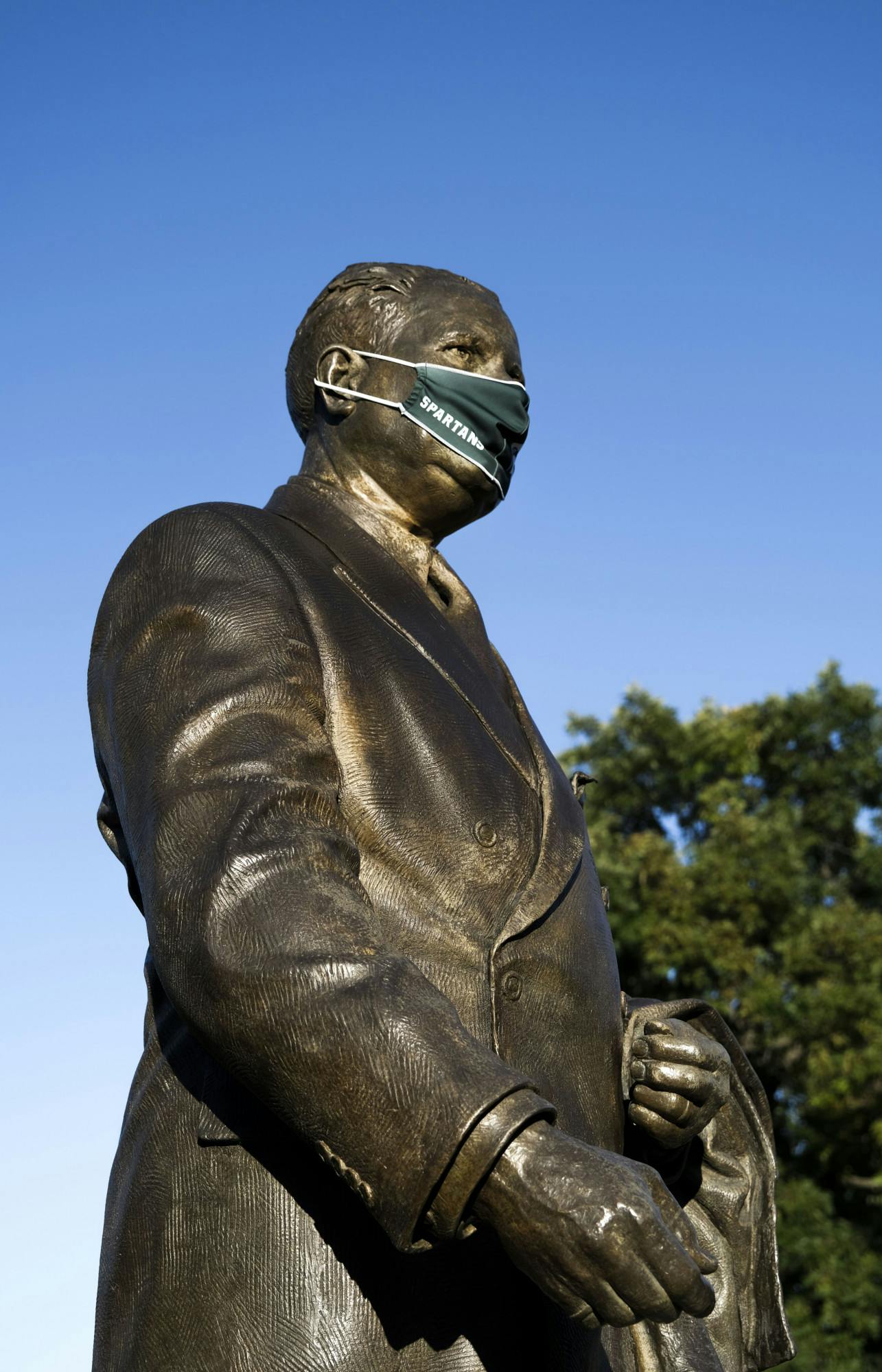 <p>Statue of President John A. Hannah with a mask on in front of the Hannah Administration Building on Sept. 20, 2020.</p>