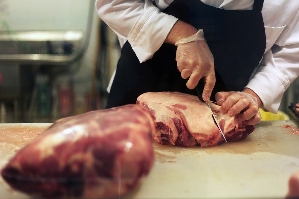 <p>Lansing resident Chris Badour cuts meat May 16, 2014, at Mert's Specialty Meats, 1870 W. Grand River Ave., in Okemos. Badour has been with the store since July of 2013. Danyelle Morrow/The State News</p>