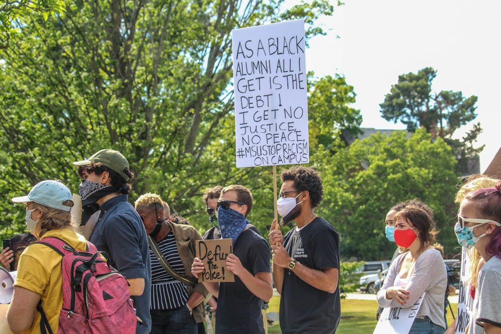 <p>Tory Conway holds up a sign during March Against Fear at Michigan State University on June 24, 2020.</p>