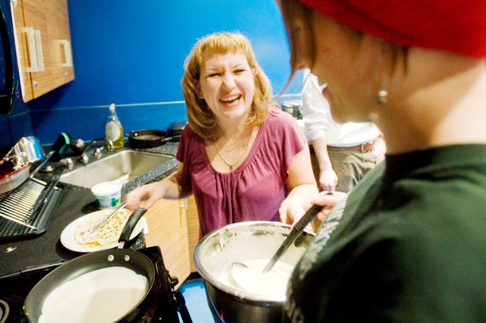 Marina Lychaeva, a Fulbright program foreign language teaching assistant on exchange to MSU, laughs Friday night at Owen Hal as she cooks blini, or little pancakes with environmental science and Russian senior Laura Young. The MSU Russian club hosted celebratory event for Maslenitsa, a religious holiday that begins a week before Great Lent. Justin Wan/The State News