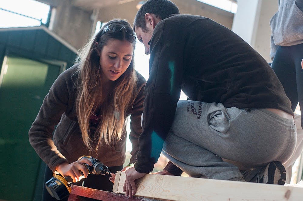 	<p>Computer engineering sophomore Goksu Adanali inserts a screw into some wood as chemistry junior Chris Gallick holds it in place Oct. 7, 2013 at Spartan Stadium. Student organizations are preparing floats for the <span class="caps">MSU</span> Homecoming parade taking place on Friday. Khoa Nguyen/The State News</p>