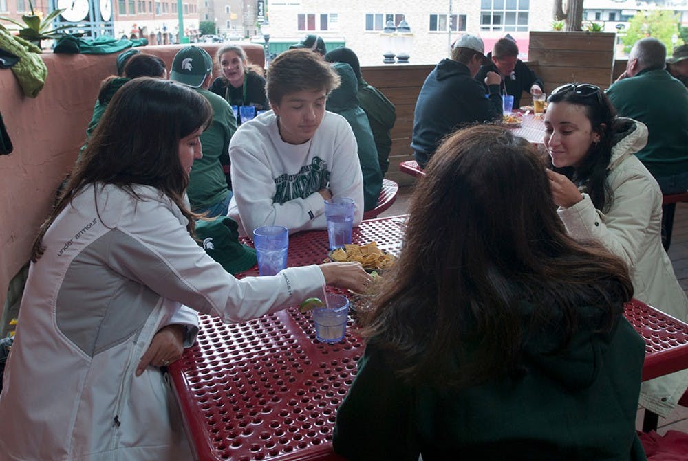 <p>Lake Orion resident Cheryl Banerian (front middle), Shelby township residents Margaret Rende and Dominic Rende, 16, (left and back middle) and Turn, Italy resident Francesca Santise  (right) eat chips and guacamole on the balcony on Sept. 12, 2015, at El Azteco, 225 Ann St. El Azteco has been open since 1976. Jack Stephan/ The State News</p>