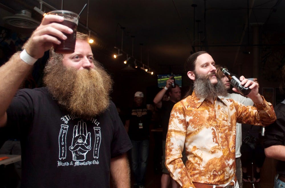 Jeff Langum, left, and Dan Roberts, right, raise their drinks at the GAFBO Great Lakes Regional BMC. Langum won 1st place in the Full Beard category and Roberts took 1st place in the Sideburns/Muttonchops category. Griffin Zotter/The State News