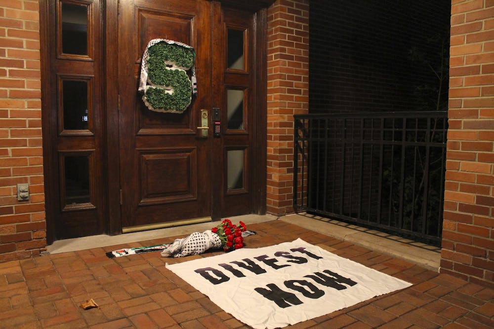 <p>Members of Students for Justice in Palestine placed roses, a "Divest Now" banner and keffiyeh at the doorsteps of Cowles House, the residence of MSU President Kevin Guskiewicz on Oct. 7, 2024.</p>