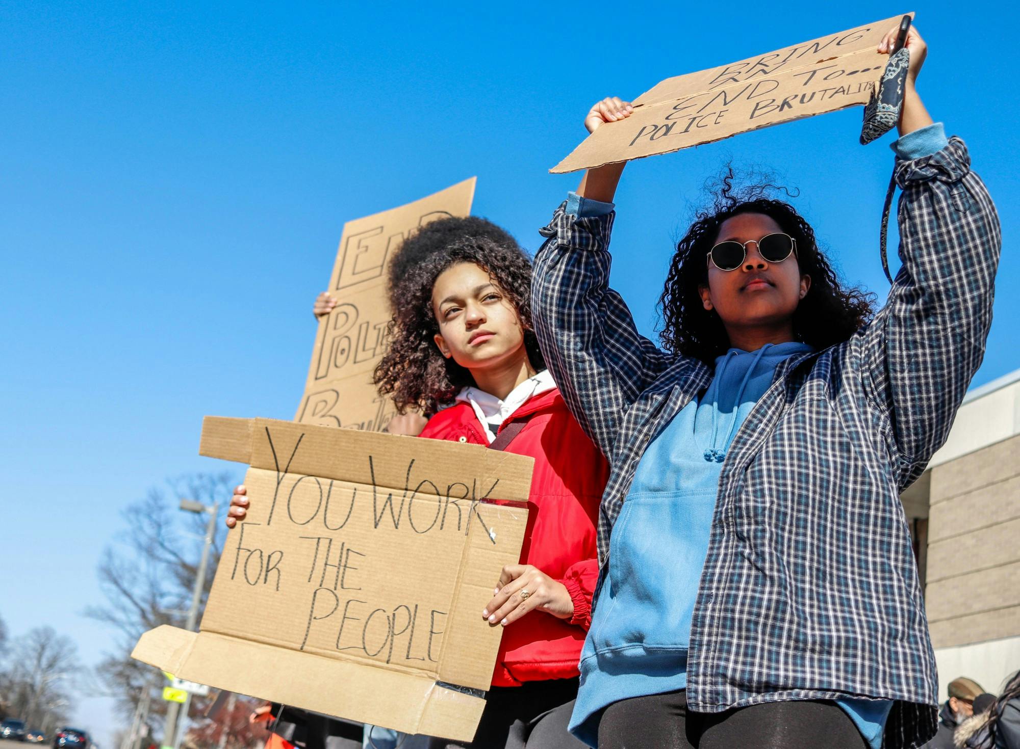 <p>Protesters Liyu Mesay, left, and Anaiss Rios-Kasoga, right, hold signs toward the road at the Lansing Police brutality protest in front of the East Lansing Police Station and 54B District Court on Feb. 23, 2020.</p>