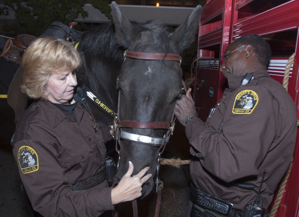 	<p>Deputized mounted police officers Brenda Mills, left, and Cleveland Mills put a bridle on Casey before their patrol ride on Friday, Sept. 28. It takes about an hour to properly saddle and prepare the horses. Julia Nagy/The State News</p>