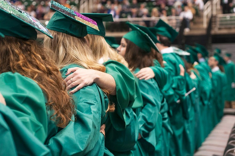 <p>Students stand together for the playing of the alma mater song &quot;Shadows&quot; during the spring convocation ceremony on May 2, 2014, at Breslin Center. Graduating seniors were honored as a whole prior to individual college commencement ceremonies. Danyelle Morrow/The State News</p>