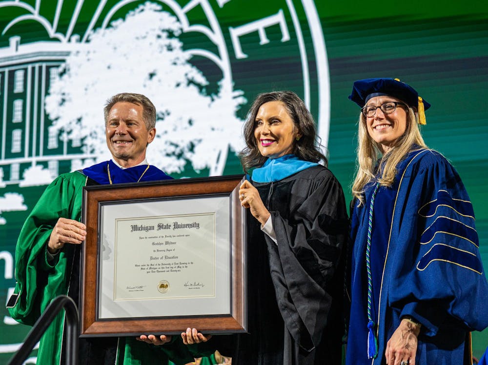 <p>Michigan State University's president, Kevin Guskiewicz (left) and Provost Laura Lee McIntyre (right) present Michigan Governor, Gretchen Whitmer with an honorary degree of Doctor of Education during a convocation inside the Breslin Center in East Lansing, Mich., on May 1, 2026.</p>