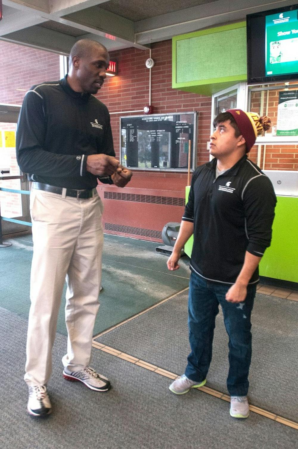 <p>MSU alumnus and Intramural Coordinator Dujuan Wiley talks to his coworker and psychology junior Angel Montalban, April 2, 2015, at IM Sports West. Wiley just started his job as Intramural Coordinator in August but says that he loves it and that it's good to be back on campus. Allyson Telgenhof/The State News.</p>