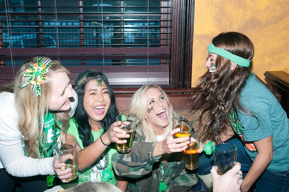 <p>From left to right, kinesiology senior Whitney Woodbridge, psychology senior Therese Diola, interdisciplinary studies in social science and health studies senior Taylor Parks and nursing senior Aubrey Dwyer enjoy a drink March 17, 2014, in the morning at Dublin Square Bar on St. Patrick's Day. Patrons crowded into the bar early morning, lining up outside around 7 a.m. Allison Brooks/The State News</p>