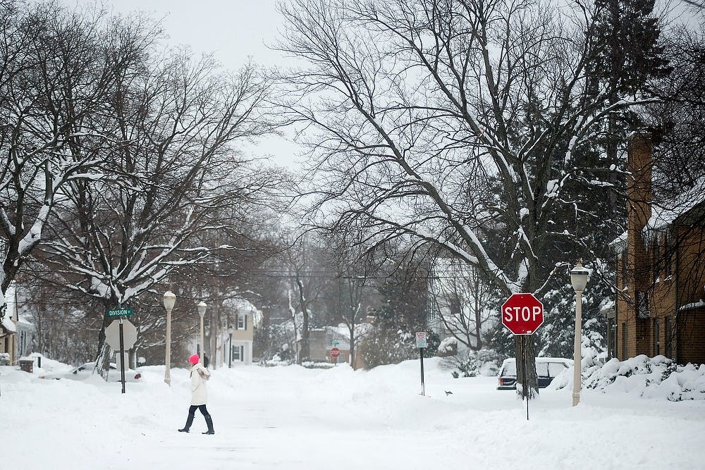 	<p>Psychology and premedical sophomore Lauren Bowen walks Jan. 6, 2014, across the intersection of Beech and Division Street. East Lansing declared a weather emergency, asking residents to not travel public streets unless necessary. Julia Nagy/The State News</p>