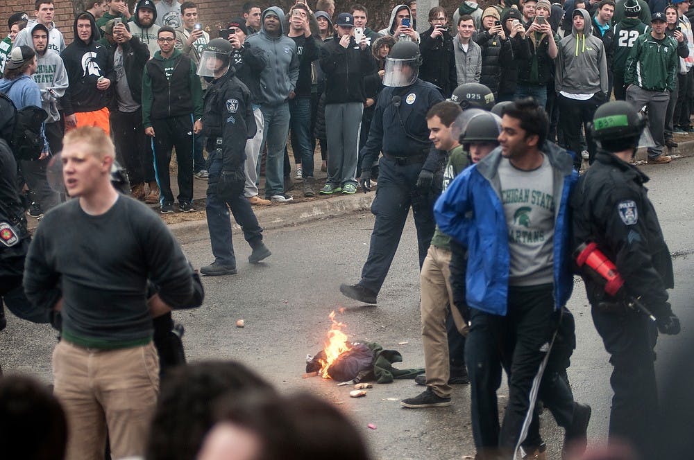 <p>Students get arrested after setting fire to a backpack and sweatshirt after the Spartan win over Louisville March 29, 2015, at Cedar Village Apartments. The State News.</p>