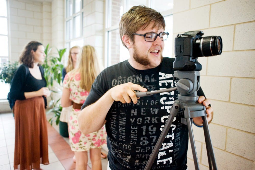 Professional writing senior Josh Compton takes a portrait Friday afternoon at CATA Transportation Center in Lansing for MSU's Creative Exploratory with Lansing resident Keith Clement (not pictured). The team of students stading behind Campton was making a documentary for the Exploratory seeking the connection between Lansing and East Lansing. Justin Wan/The State News