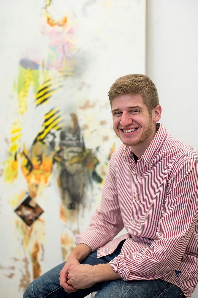 <p>Graduate student Samuel Bennett poses for a portrait in front of one his art pieces Oct. 21, 2014, at the Kresge Art Center. Bennett said he draws inspiration from the beautiful and ugly things in life. He started with painting and has recently gone more into collage work. Julia Nagy/The State News</p>