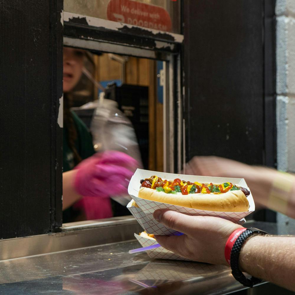 <p>A University Weiner employee serves a customer their custom hot dog with chili, ketchup, mustard, and relish on top in East Lansing, MI on April 17, 2026.</p>