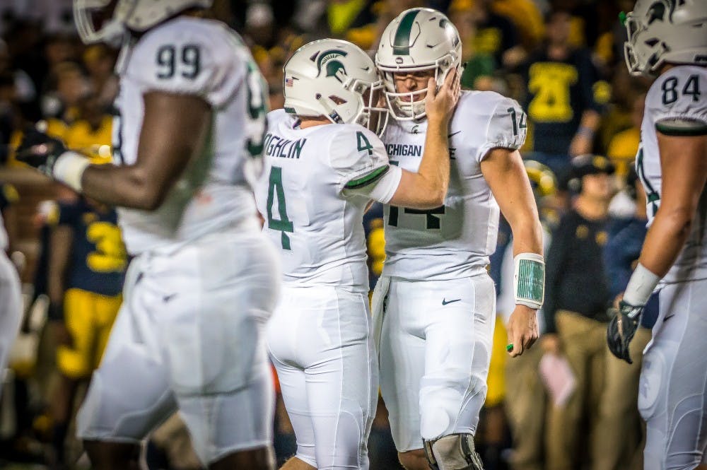 <p>Redshirt freshman kicker Matt Coghlin (4) congratulates sophomore quarterback Bryan Lewerke (14) after his touchdown during the game against Michigan on Oct. 7, 2017 at Michigan Stadium. The Spartans defeated the Wolverines, 14-10.</p>