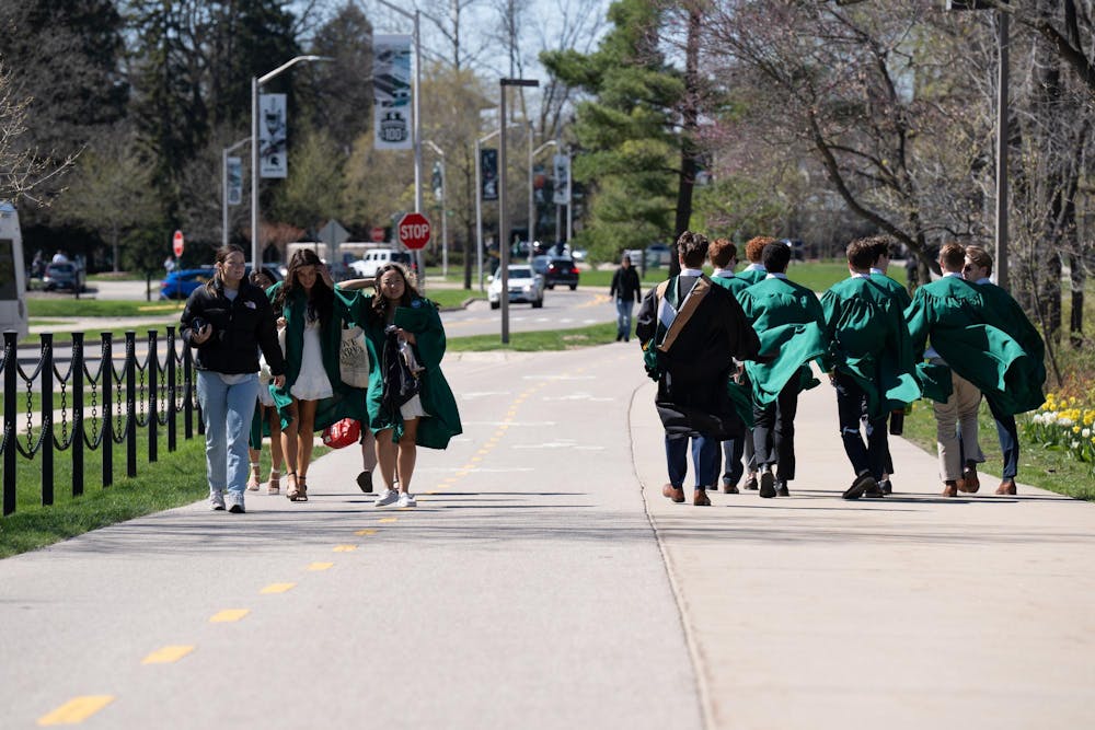 Groups of seniors walk across the Michigan State University campus on April 19, 2024. Seniors often have to wait in line for the best spots on campus to get their portraits taken. 