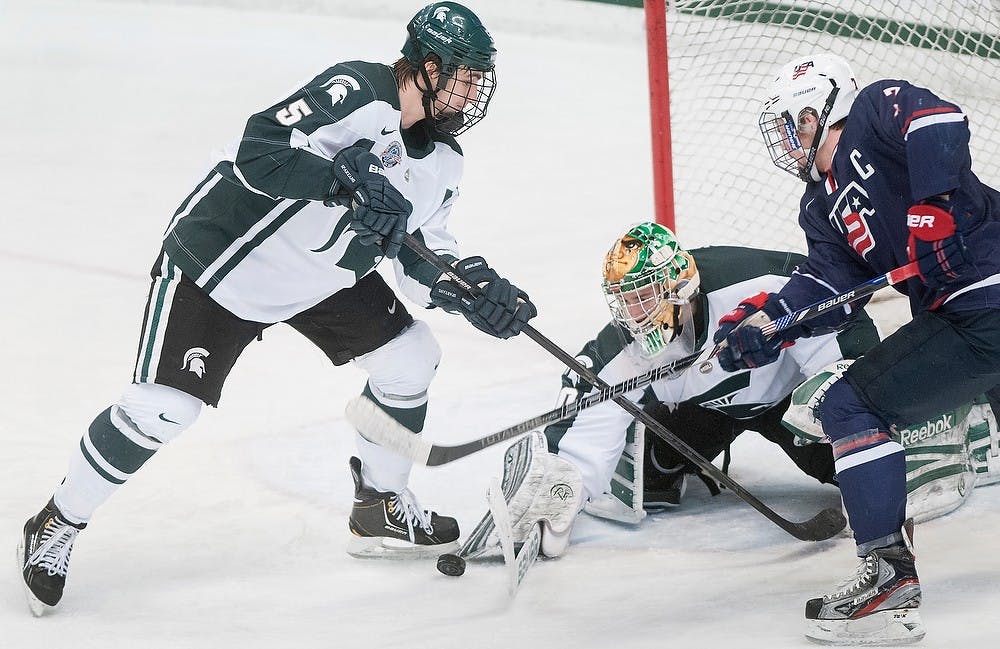 	<p>Freshman goalie Jake Hildebrand tries to cover the puck as Sophomore defenseman RJ Boyd defends U.S. National Team Development Program defenseman Scott Savage during the game Tuesday, Jan. 22, 2013 at Munn Ice Arena. U.S. <span class="caps">NTDP</span> defeated the Spartans 3-0. Danyelle Morrow/The State News</p>