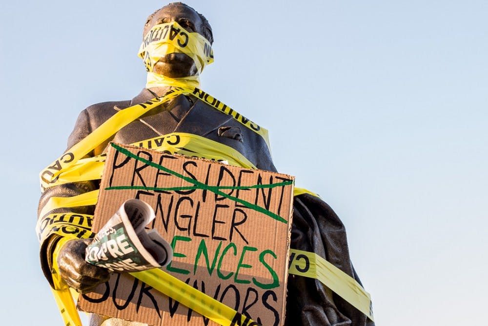 <p>The statue of John A. Hannah stands wrapped with caution tape on April 20, 2018 at the Hannah Administration Building. The rally was organized by students and Nassar survivors to call for the resignation of the Board of Trustees.</p>