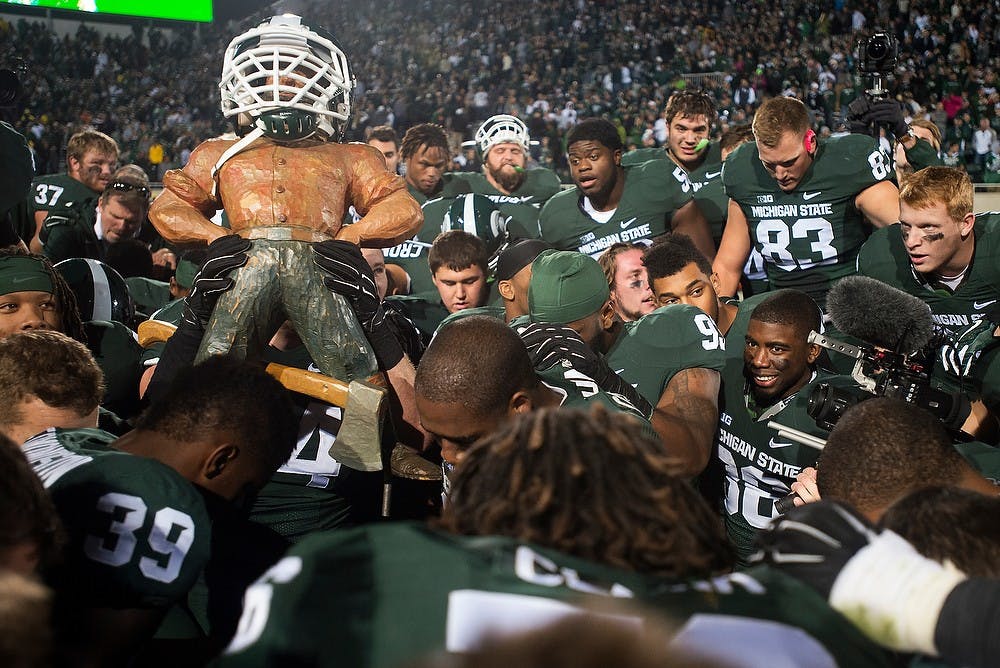 <p>The team prays with the Paul Bunyan Trophy on Oct. 25, 2014, after the game against Michigan at Spartan Stadium. The Spartans defeated the Wolverines, 35-11. Julia Nagy/The State News</p>