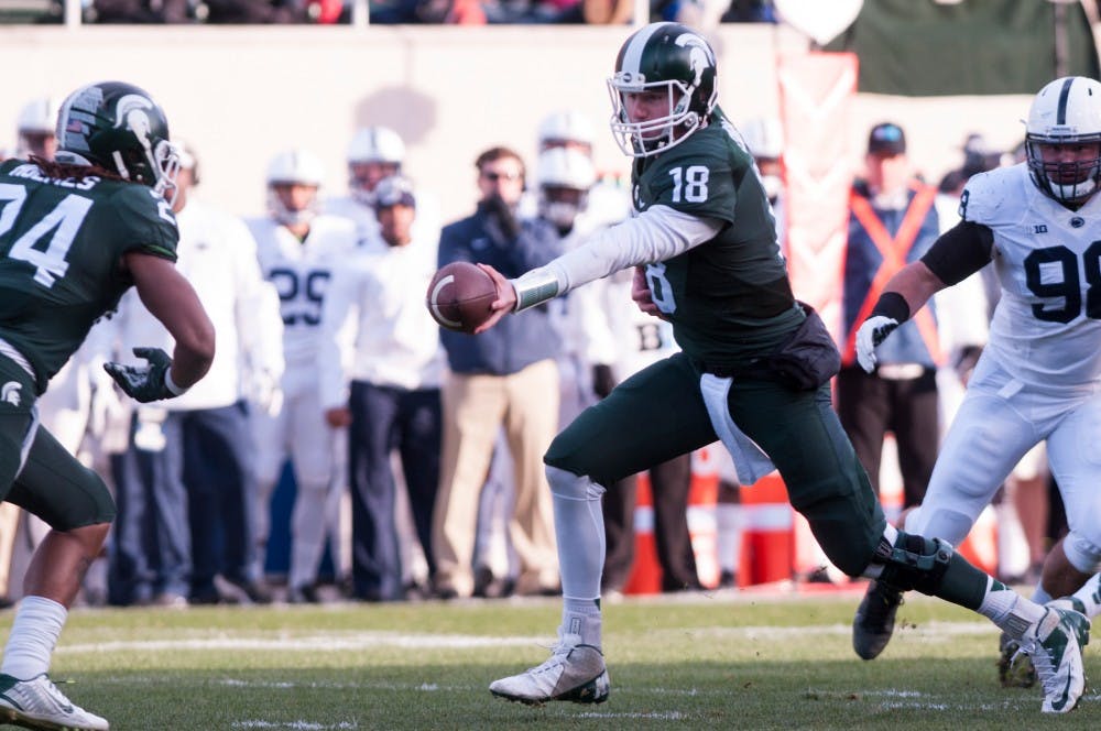 Senior quarterback Conner Cook, 18, hands off the ball to sophomore running-back Gerald Holmes, 24, during the first quarter of the game against Penn State on Nov. 28, 2015 at Spartan Stadium. The Spartans defeated the Nittany Lions, 55-16.
