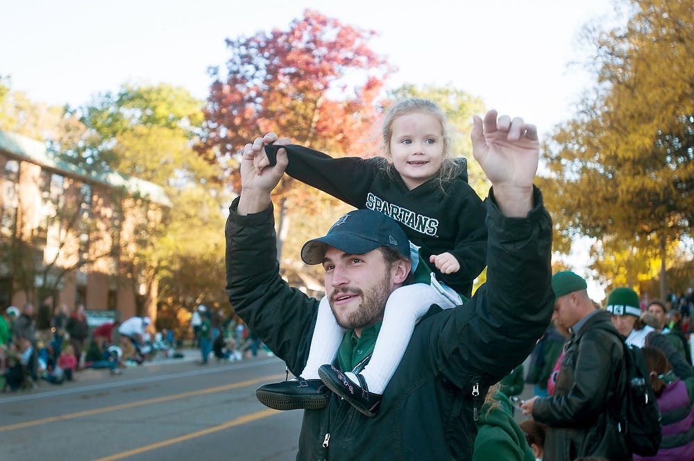 	<p>East Lansing resident Ben Stone holds daughter Emma on his shoulders on Friday October 12, 2012 at the Homecoming parade. </p>